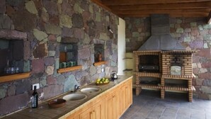 Una cocina con paredes de piedra, armarios de madera y un horno de pizza integrado.