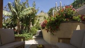 Un jardín con un banco, una mesa con fruta y una escalera que lleva a un edificio.