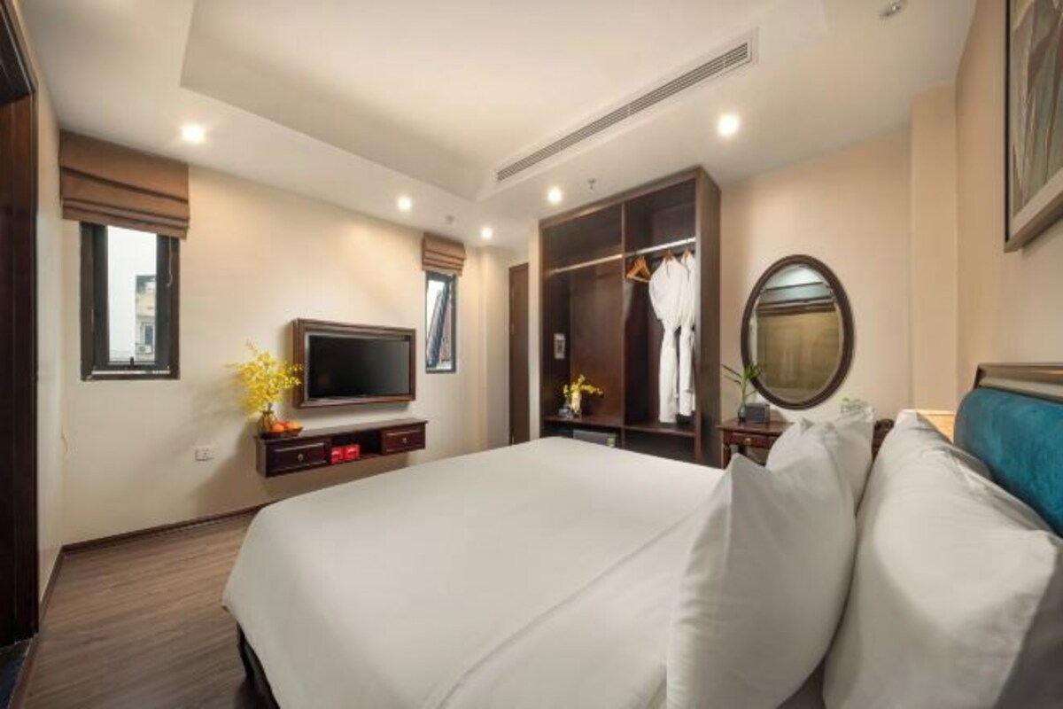 A hotel room with a large bed, a TV, a wardrobe, and a mirror.