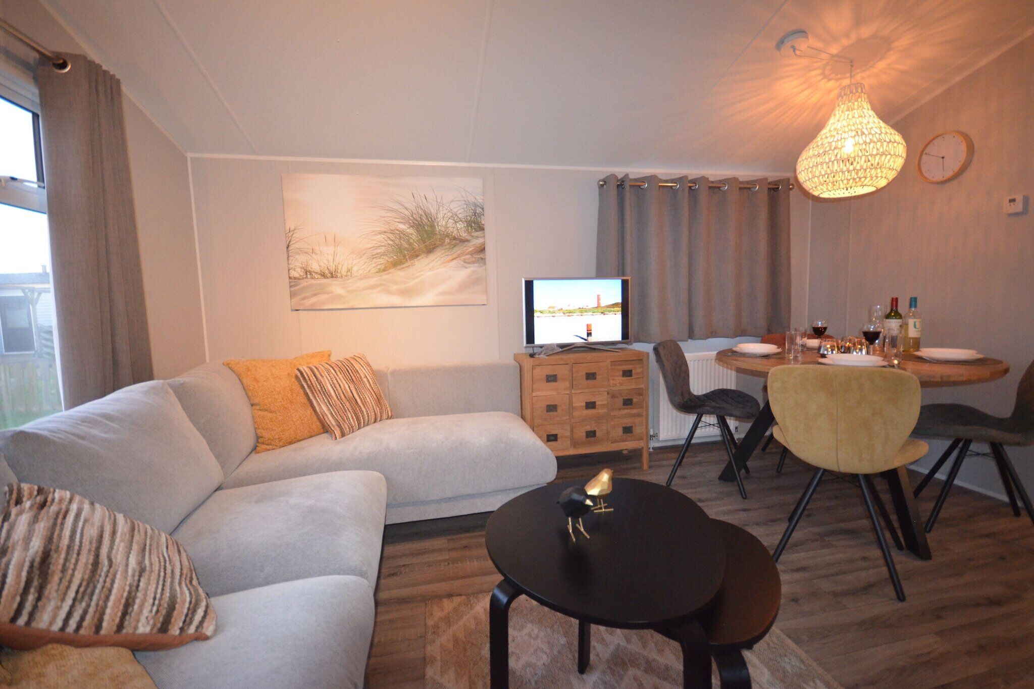 A modern living room with a sofa, a coffee table, and a dining area with chairs and a table set for two.