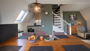 Eine moderne Küche mit Oberlicht, ein Essbereich mit Holztisch und eine Treppe, die zu einer weiteren Ebene führt.