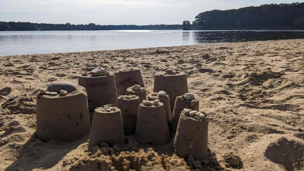 Ein sandiger Strand mit mehreren Sandskulpturen.