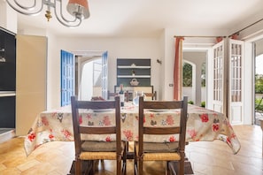 Enjoy meals in this stylish dining area with a table for four, a chandelier, and a view of the outdoors.