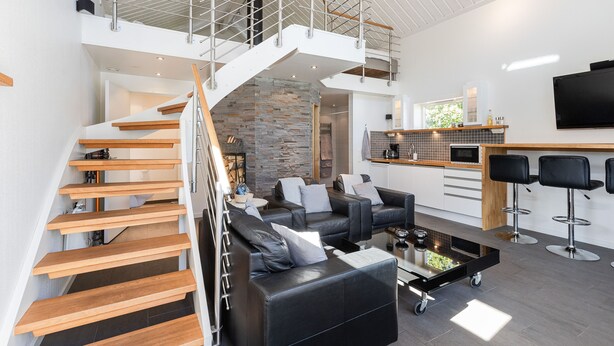 Een modern interieur met een trap, zithoek, keuken en een televisie.