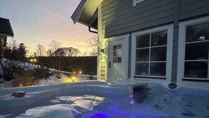 Een huis met een oprit bedekt met sneeuw en een zichtbare buitenlamp.