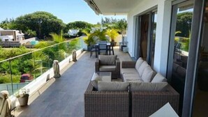 A balcony with wicker furniture, a table, and a chair. - Penthouse avec Jacuzzi Privé à Pereybère (Grand Baie)