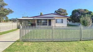 A single-story house with a fenced yard, a covered porch, and a clear sky. - Comfortable 2-Bedroom home “Rest Easy Mudgee” (Mudgee)