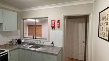 A compact kitchen with a built-in oven, a sink, and a window above the counter.