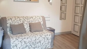 A room with a sofa, a small table, a mirror, and a door. - Renovated central studio, 50 m from cable car, 2-4 pers (Cauterets)