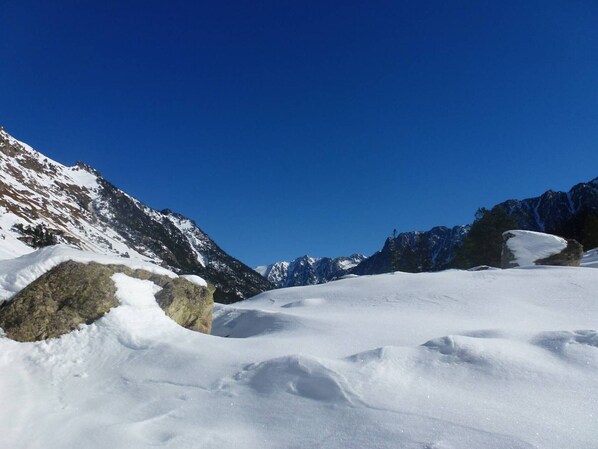 A snow-covered mountain landscape with rocky outcrops and clear blue skies.