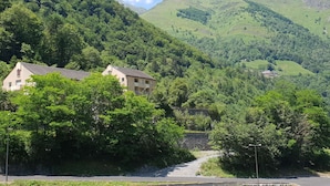 A rural setting with a road leading to a building surrounded by lush green hills.