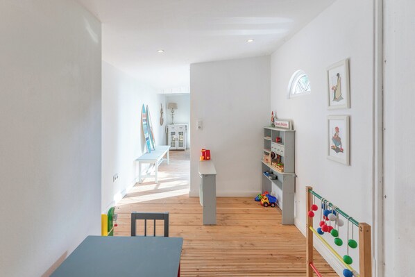 A bright, modern room with a wooden floor, a small table, and a play area with toys and a ball rack. - The Grosse Lachmöwe semi-detached house in St. Peter-Böhl for up to 6 people (St. Peter-Böhl)