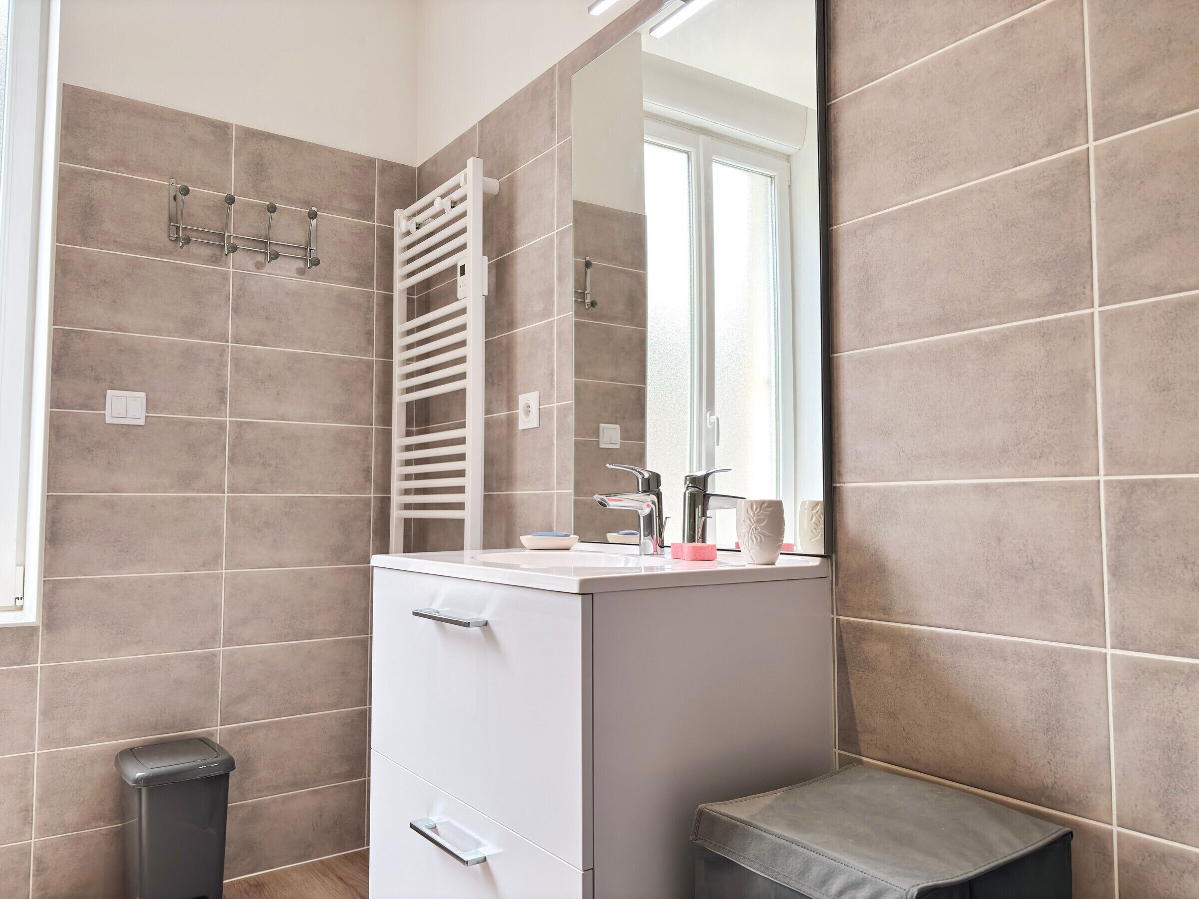 A bathroom with a white sink, mirror, and towel rack.