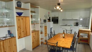 Cozinha com armários brancos, mesa de jantar de madeira e micro-ondas.