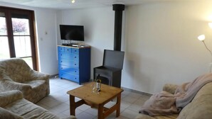 Uma sala de estar com sofá, mesa de centro, televisão, armário azul e lareira.