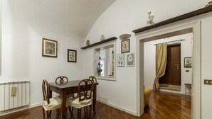 Una zona menjador amb taula i cadires de fusta, un radiador i quadres a les parets.
