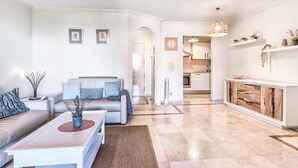 A modern living room with a sofa, coffee table, and decorative items. A kitchen is visible in the background. - Bahia - Bencomo 1.2 PARTIAL SEA VIEW & NATURE RESERVE 1B (Arona)