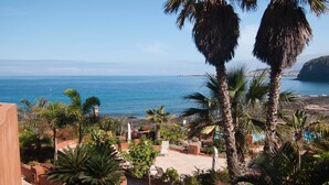 A coastal view with a patio area, palm trees, and a clear blue sea. - Bahia - Bencomo 1.2 PARTIAL SEA VIEW & NATURE RESERVE 1B (Arona)