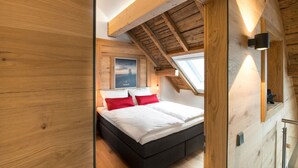 Ein Schlafzimmer mit schrägem Dach, Holzwänden und einem Oberlicht.