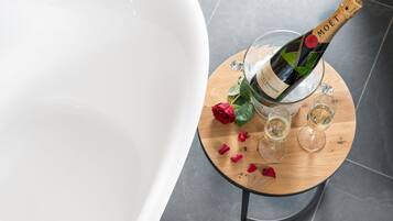 Une bouteille de champagne Moët, deux verres et une rose sur une table en bois dans une salle de bain.