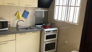 A compact kitchen with a microwave, sink, stove, and oven.