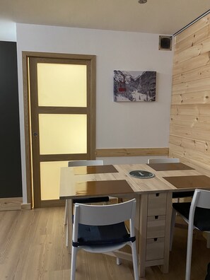 A dining area with a wooden table and chairs, a large frosted glass door, and a framed picture on the wall.