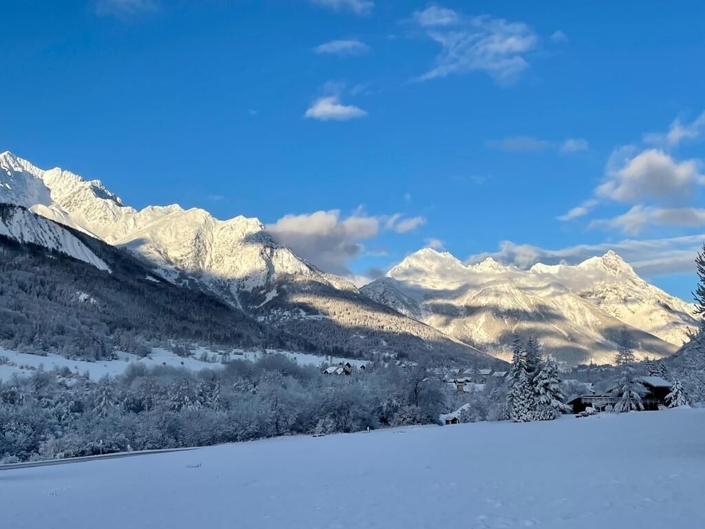 Un paysage de montagne enneigé, sous un ciel dégagé.