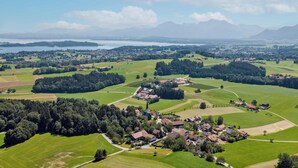 Luchtbeeld van een landelijk dorp met huizen, groene velden en een kerk.