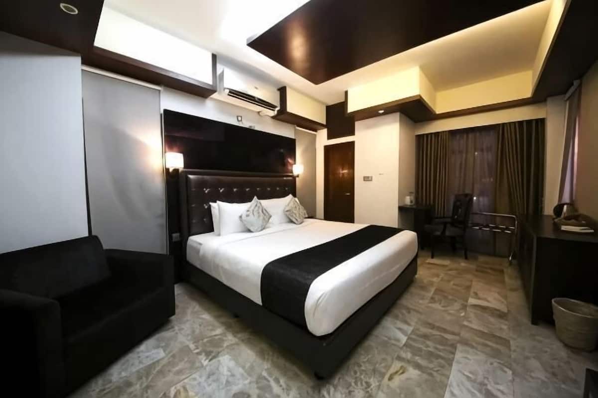 A modern hotel room with a large bed, a seating area, and a desk.