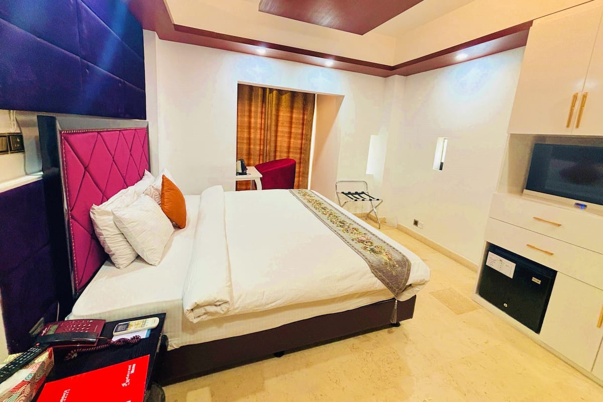 A hotel room with a bed, a TV, a desk, and a chair.