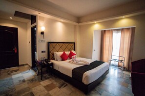 A hotel room with a large bed, a nightstand, a desk, and a chair. - The Elite Residence Dhaka. (Dhaka)