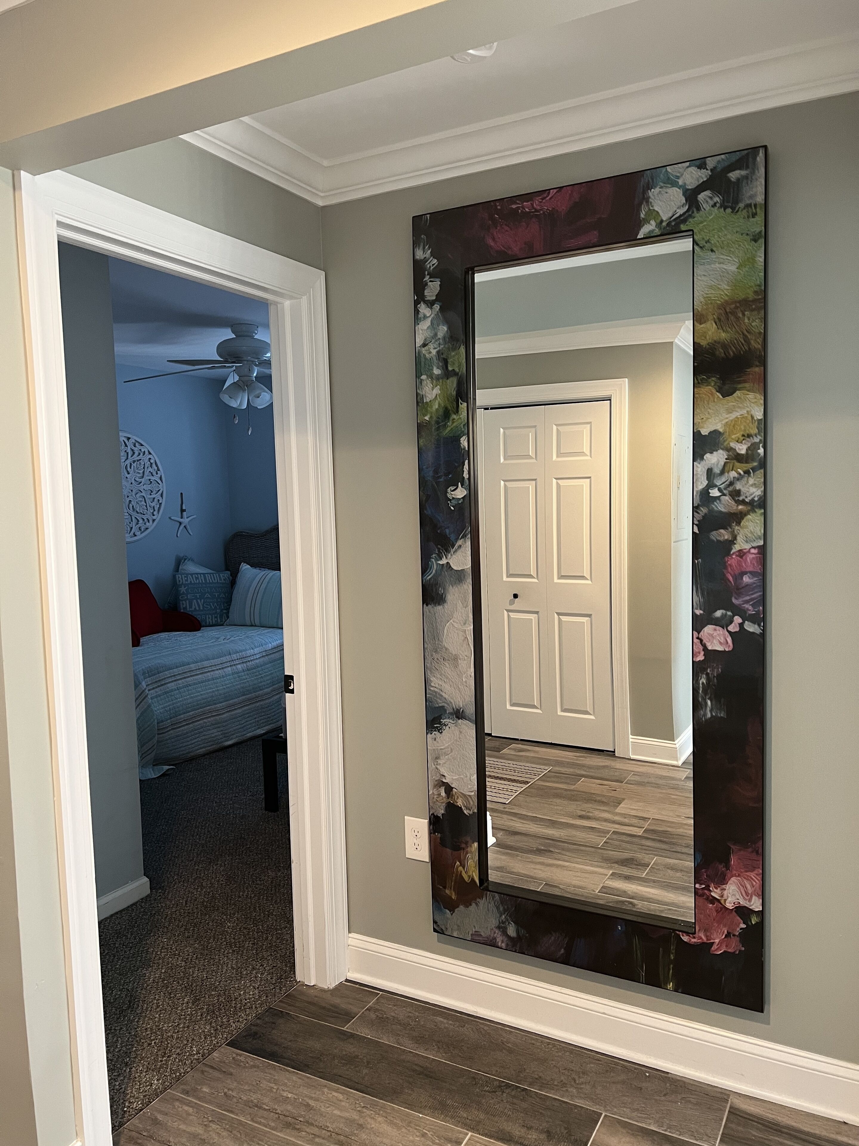 A hallway with a door, a wall with a floral painting, and a bed with a blue wall and a starfish decoration.