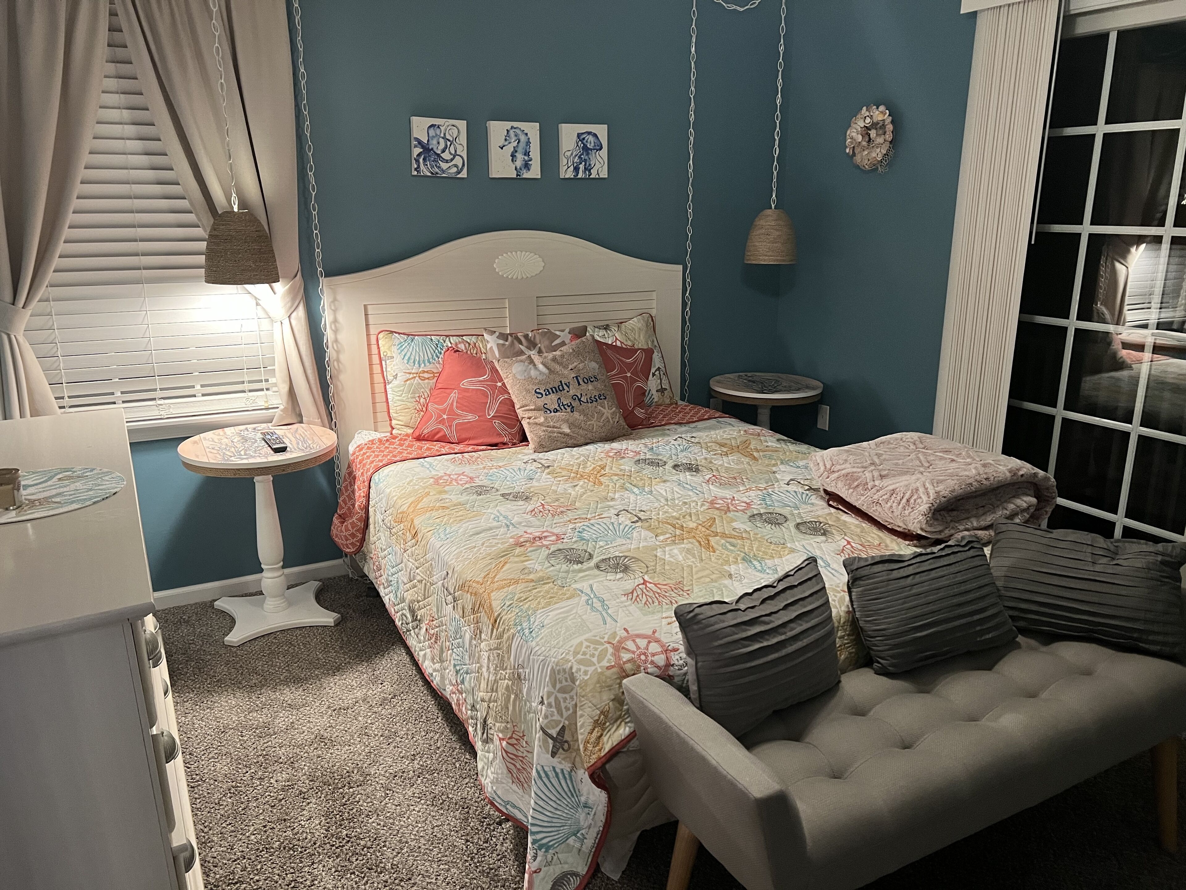 Un dormitorio con cama, mesitas de noche, una silla y una ventana.