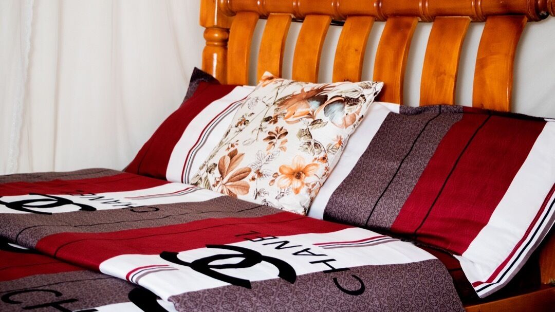 A bed with a striped blanket and floral pillow.