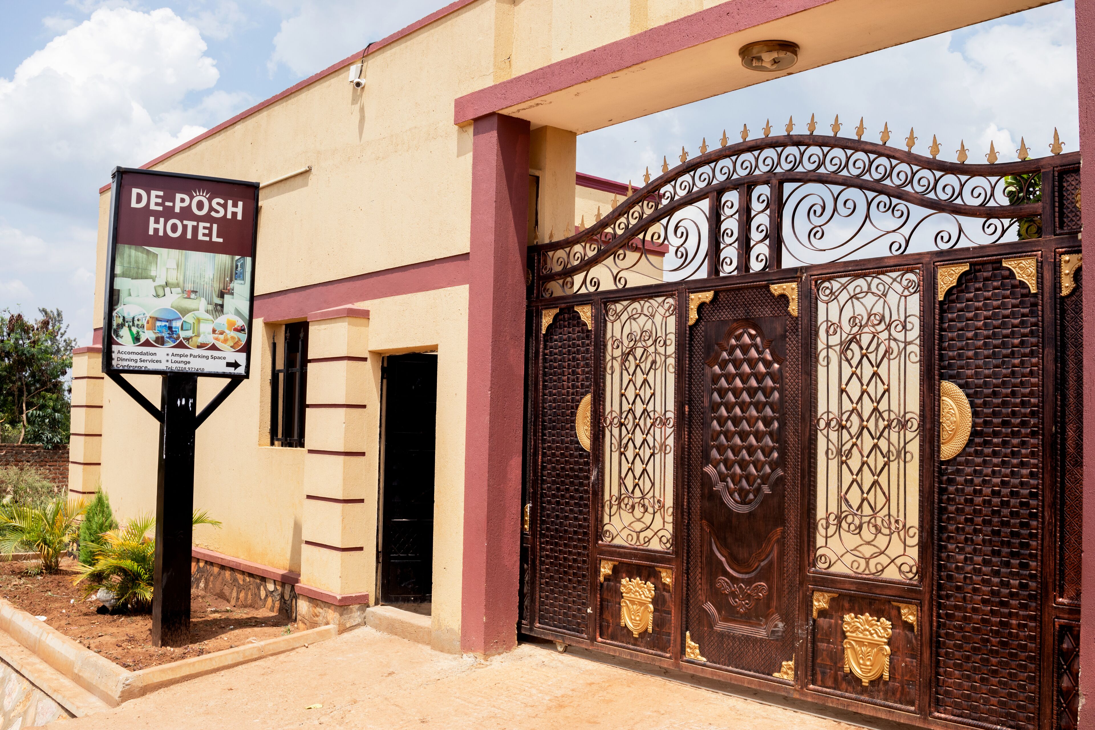 A hotel entrance with a wrought iron gate and a signboard.