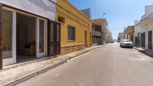 A street view with buildings, a parked car, and a clear sky.
