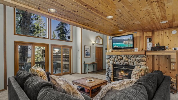 A cozy living room with a fireplace, large windows, and a television. - Martis Valley Vistas: Family Home w/ Private Hot Tub, 2 Living Rooms, near Golf (Truckee)