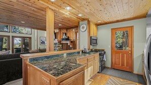 A modern kitchen with wooden cabinets, a granite countertop, and a built-in microwave. - Martis Valley Vistas: Family Home w/ Private Hot Tub, 2 Living Rooms, near Golf (Truckee)