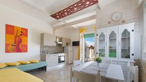 A cozy room with a bed, a dining table, and a kitchen area. - 1960 Villa Aurora - Mono Aury by Barbarhouse (Porto Cesareo)