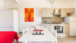 A modern kitchen with white cabinets, a gas stove, and a built-in oven. There is a dining table with a red tablecloth and four mugs. - 1960 Villa Aurora - Mono Aury by Barbarhouse (Porto Cesareo)