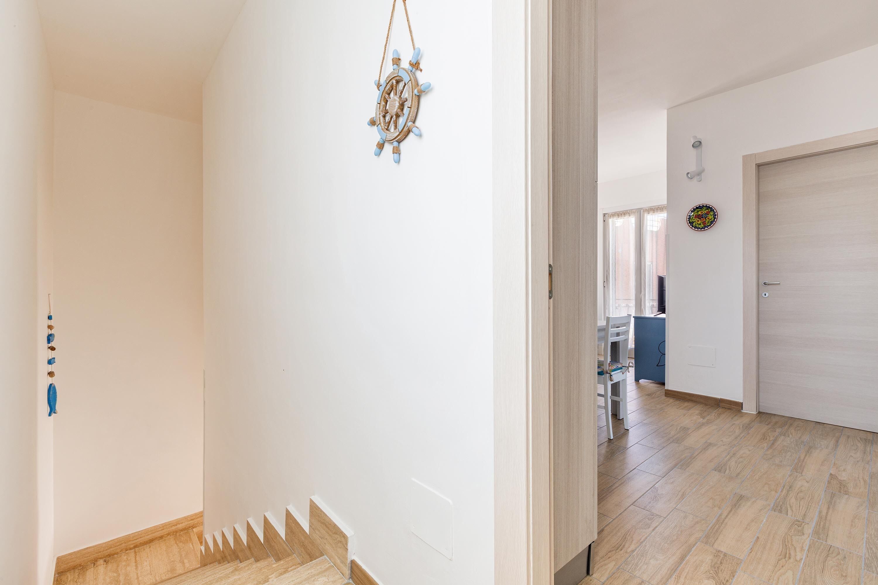 A hallway with a wooden staircase, a door, and a wall-mounted decorative item.