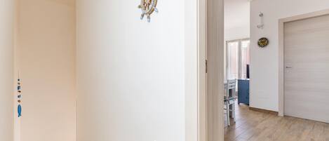 A hallway with a wooden staircase, a door, and a wall-mounted decorative item.