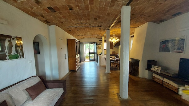 Ein geräumiger Wohnbereich mit Holzboden, einer Couch, einem Esstisch und einem Kamin.