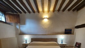 Ein Schlafzimmer mit einem hölzernen Bett, zwei Nachttischlampen, einem Heizkörper und einem an der Wand befestigten Regal mit einem Bild.