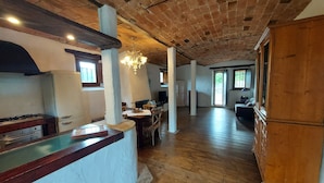 Eine geräumige Küche mit Holzausstattung, einem Gasherd und einem Kühlschrank. Es gibt einen Essbereich mit Tisch und Stühlen sowie ein Wohnzimmer mit einer Couch und einem Fernseher.