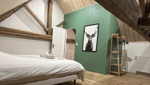 A bedroom with a wooden floor, a bed, a white door, a framed deer picture, and a wooden ladder. - Former high-capacity factory in the heart of Chagny (Chagny)