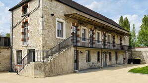 A two-story stone building with a balcony, a staircase, and a paved driveway. - Former high-capacity factory in the heart of Chagny (Chagny)
