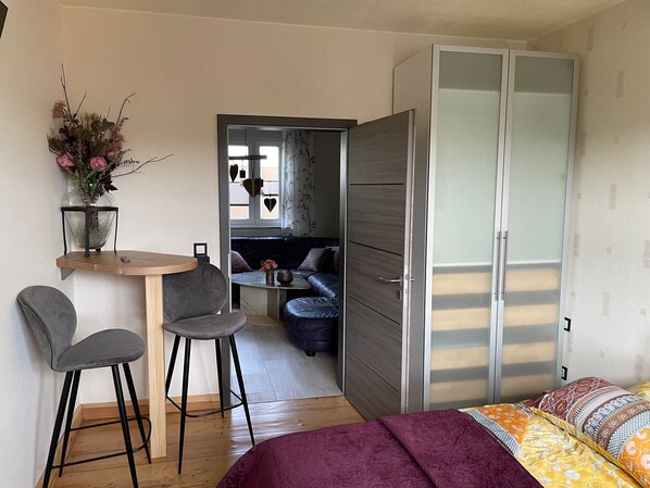 Un dormitorio compacto con cama, escritorio con dos sillas, sofá y armario.