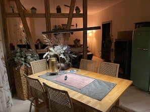 Un comedor con mesa de madera, sillas de mimbre y un florero con flores.