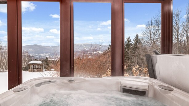 Een hottub met uitzicht op een prieel en bergen.